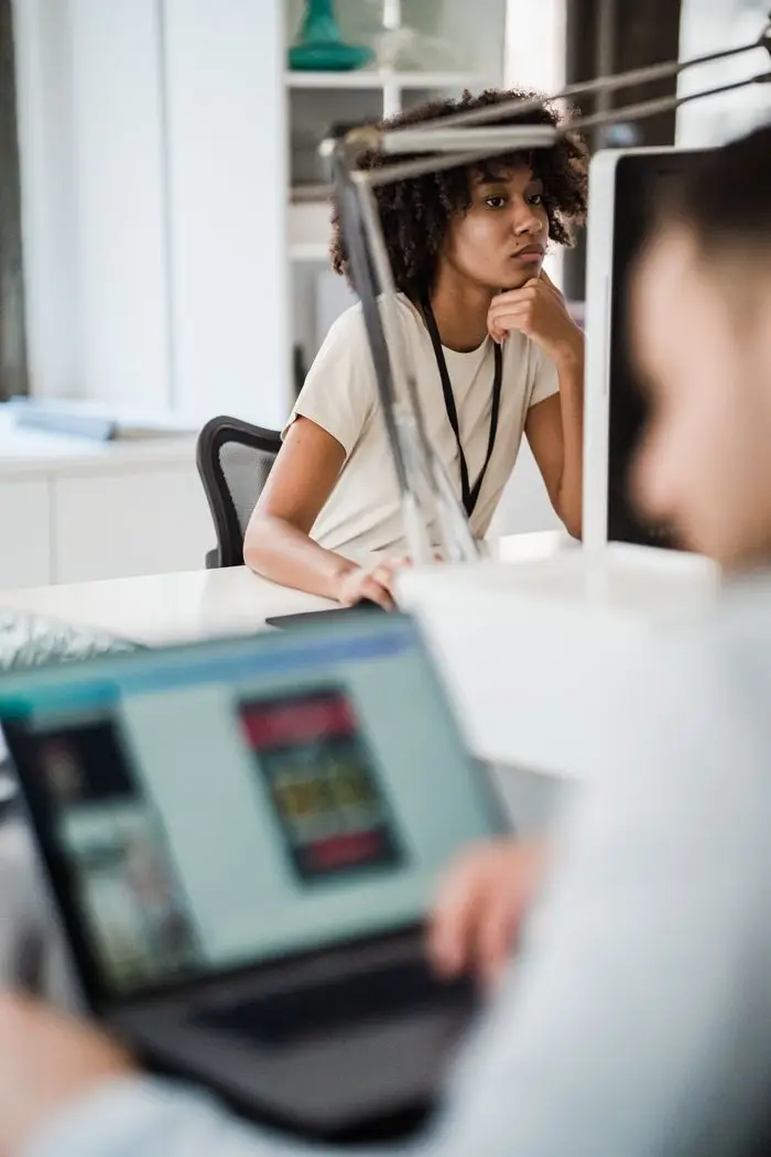 Young professionals working in a modern office setting, focused on computer screens.