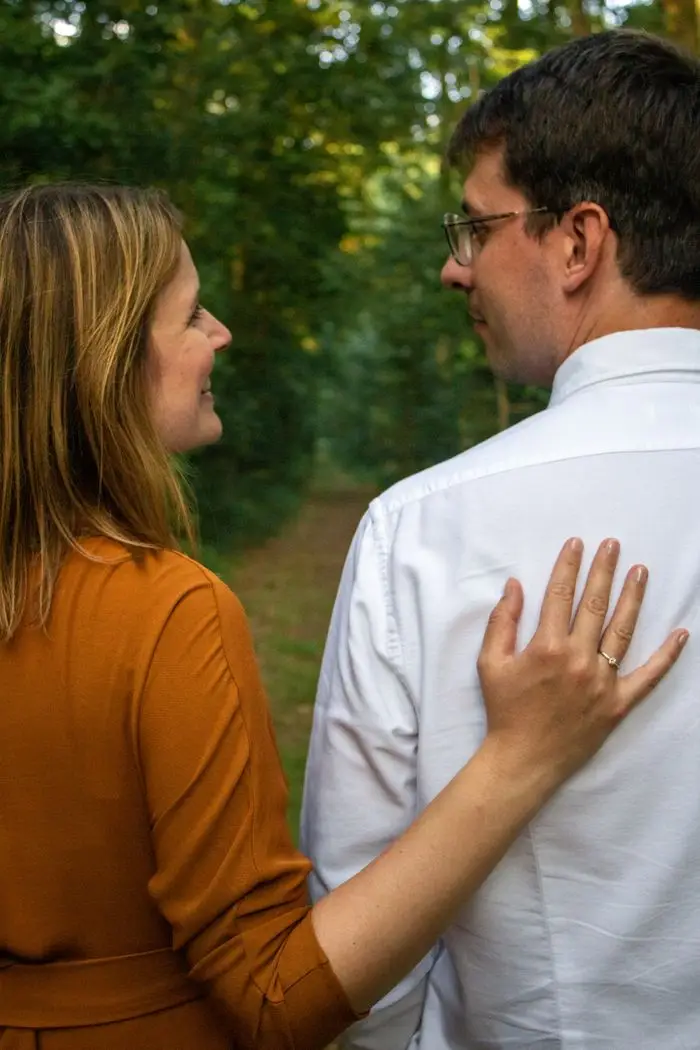 A smiling couple lovingly embracing on a serene forest path.