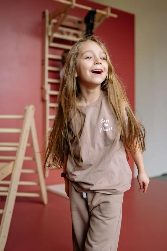 Happy young girl in brown clothing playing indoors with vibrant background.